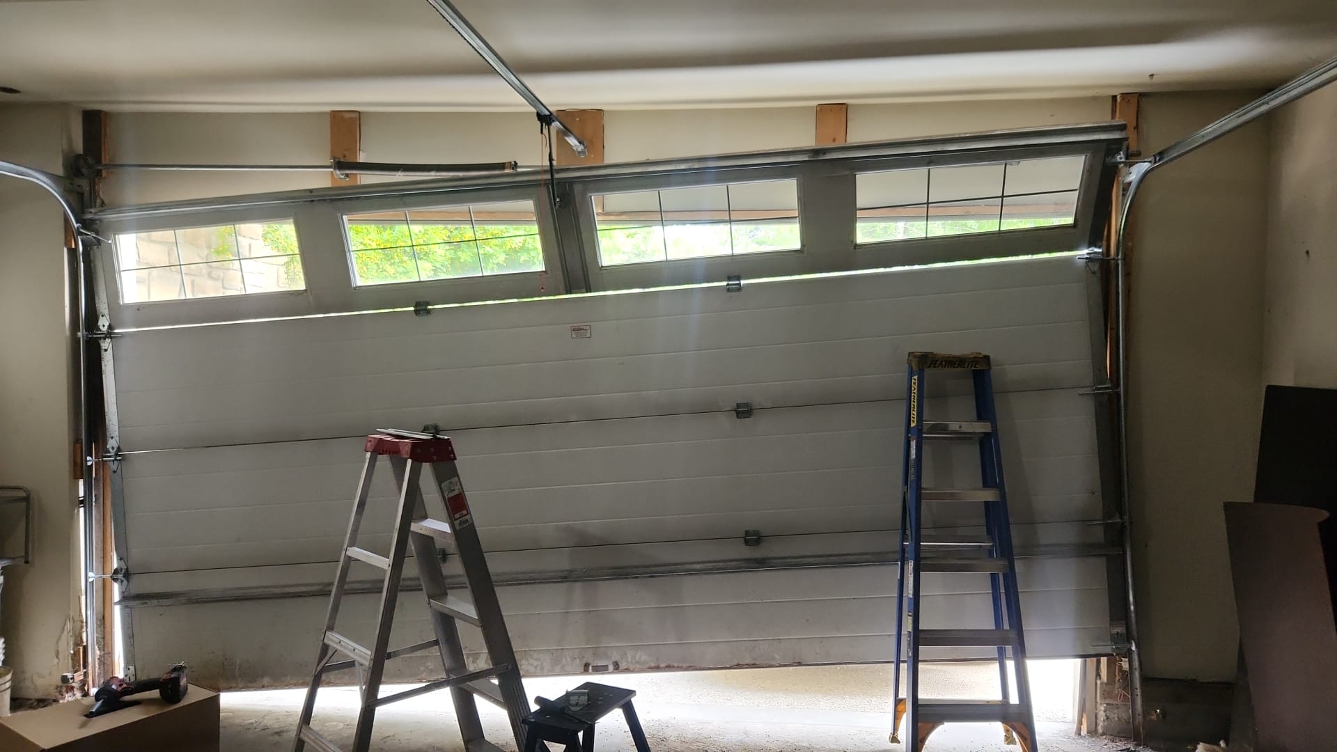 Sectional garage door hanging crooked and partly outside its tracks